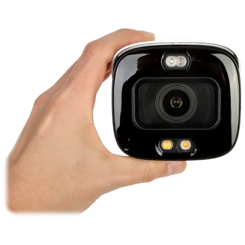 A person is holding a sleek, black security camera with a prominent lens and two LED lights below it. The camera features a glossy finish and compact design, suitable for modern surveillance needs.