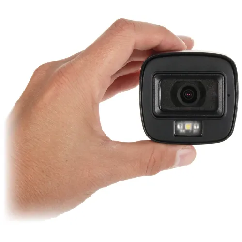 A hand holds a compact black camera with a lens and LED lights on the front. The camera is designed for easy handling and portability.