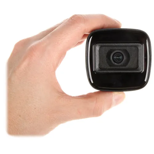 A compact black security camera is held between a person's fingers, showcasing its sleek design and lens. The camera's minimalist appearance highlights its suitability for discreet surveillance.