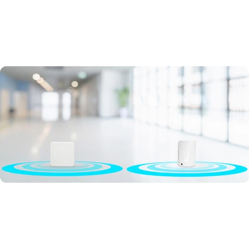 The image shows two wireless motion detectors placed on a smooth, reflective surface with blue signal waves emanating from each device. The background features a bright, modern hallway with large windows and soft lighting.