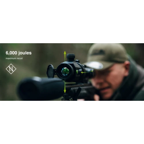 A person is aiming through a thermal imaging monocular mounted on a rifle, with a focus on the device's lens and controls. The image highlights the product's capability to withstand up to 6,000 joules of recoil.