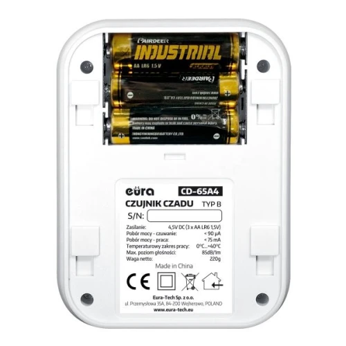 The image shows the back of a carbon monoxide detector with a battery compartment holding three AA batteries. The device features a label with technical specifications and manufacturer details.