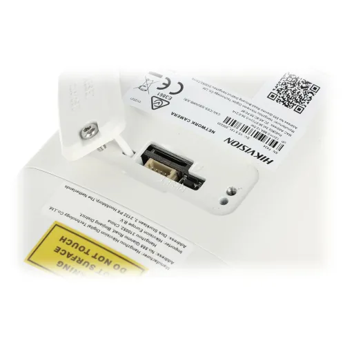 The image shows a close-up of a Hikvision network camera featuring an open memory card slot. The camera's casing is white, with visible certification markings and a QR code.