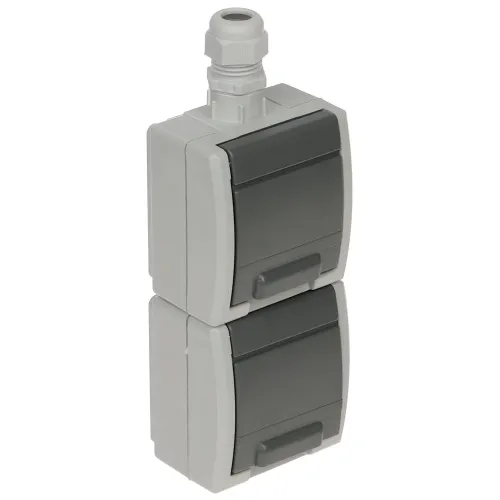 The image shows a gray, double-socket, surface-mounted electrical outlet with protective covers, designed for outdoor use. It features a robust, weather-resistant construction with an IP65 rating, suitable for various environments.