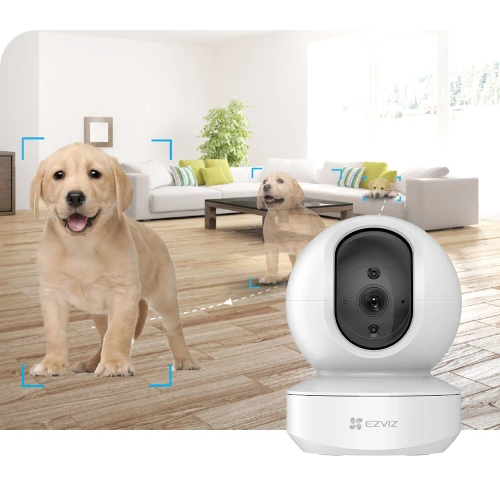 A sleek, white EZVIZ TY1 Full HD IP camera is prominently displayed in a modern living room setting, showcasing its ability to track and focus on a playful puppy. The camera's design is compact and stylish, blending seamlessly with contemporary home decor.