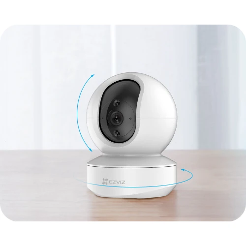 A sleek, white EZVIZ TY1 camera with a spherical design is positioned on a wooden surface, featuring a prominent lens and a rotating base for comprehensive surveillance coverage. The camera's modern aesthetic is complemented by its full HD capability, making it ideal for home security.