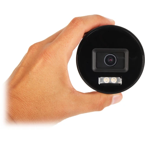 A person is holding a compact, cylindrical IP camera with a lens and LED lights visible on the front. The camera is designed for security purposes, featuring a sleek black finish.