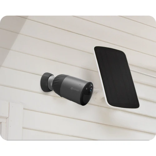 A sleek black WiFi security camera is mounted on a white wall, featuring a modern cylindrical design. Next to it, a solar panel is installed, providing a sustainable power source for the camera.