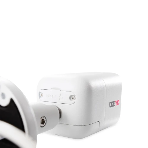 A white, rectangular IP camera with a sleek design features a visible reset button and a sturdy mounting bracket. The brand name "KEEYO" is printed on the side in contrasting colors.