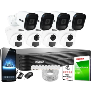 The image shows a comprehensive home security system featuring four BCS surveillance cameras, a digital video recorder, and a Toshiba surveillance hard drive. Additional components include a smartphone for remote monitoring, a mouse, cables, and a warning sign.