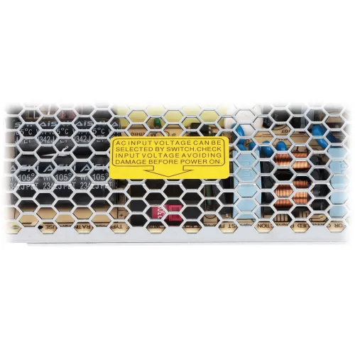 The image shows a power supply unit with a honeycomb grille, revealing internal components like capacitors and coils. A yellow label on the grille advises checking and selecting the correct AC input voltage to prevent damage.