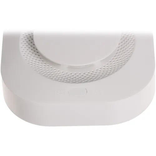 A white, rectangular device with a circular button in the center, featuring textured detailing around the button. The device has "TEST" and "MUTE" labels near the button, indicating its functionality.