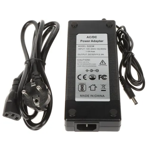 The image shows a black AC/DC power adapter with a label detailing its specifications, including an input of 100-240V and an output of 12V. It comes with two attached cables, one with a European plug and the other with a connector for electronic devices.