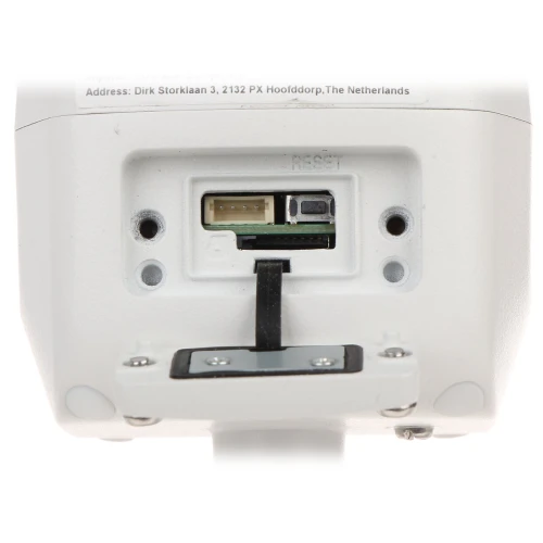 The image shows the underside of a white electronic device with an open cover, revealing a reset button and various connection ports. The device features a sleek design with visible screws and a label displaying an address.