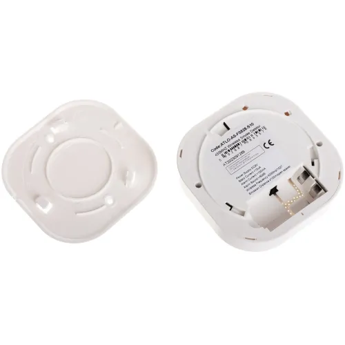 The image shows a white, square-shaped smoke detector base with mounting features and connection terminals. The base includes a label with technical specifications and compliance markings.