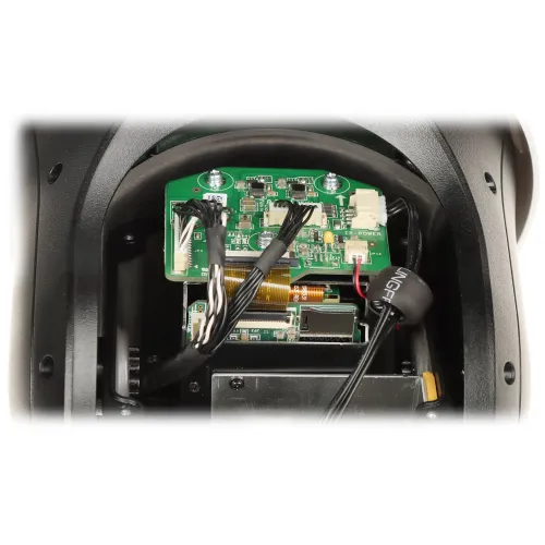 The image shows the internal components of an electronic device, featuring a green circuit board with various connectors and wires. The setup is housed within a black casing, highlighting intricate wiring and electronic parts.