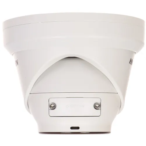 A white, dome-shaped security camera with a sleek design is shown from a side angle, highlighting its sturdy construction and mounting base. The camera features a setting adjustment panel, emphasizing its functionality and ease of installation.