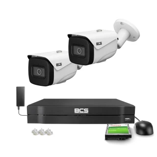 The image shows a BCS surveillance system featuring two white security cameras with sleek, modern designs. Included in the set are a black digital video recorder, a hard drive, a power adapter, and several connectors, providing a comprehensive monitoring solution.