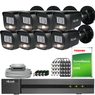 The image shows a comprehensive surveillance system package, including six black security cameras, a digital video recorder, and a Toshiba surveillance hard drive. Additional components such as cables and connectors are also included, providing a complete setup for monitoring needs.