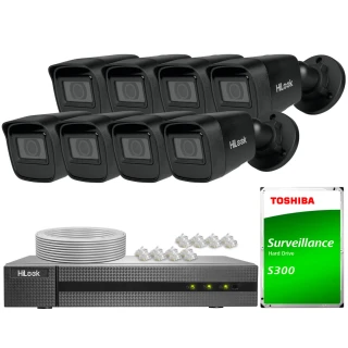The image shows a comprehensive surveillance system featuring eight black HiLook security cameras, a digital video recorder, and a Toshiba S300 surveillance hard drive. Included are cables and connectors, providing a complete setup for monitoring and recording.
