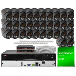 The image shows a comprehensive IP surveillance system featuring multiple black dome cameras, a surveillance hard drive, and network equipment. The set includes a DVR, cables, and connectors, designed for extensive security monitoring.