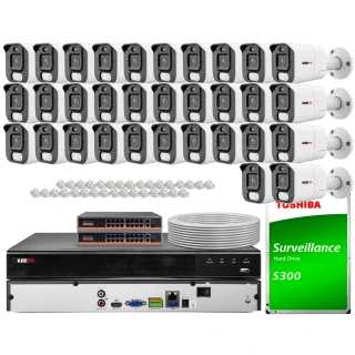 The image shows a comprehensive IP surveillance system featuring multiple white security cameras, a network video recorder, and a Toshiba surveillance hard drive. The set includes cables and connectors, providing a complete solution for monitoring and recording.