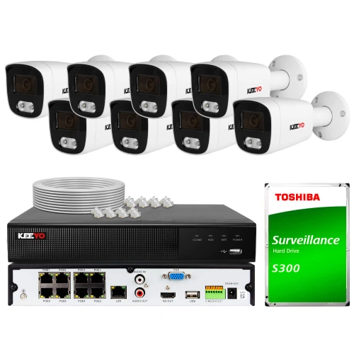 The image shows a comprehensive surveillance system package, including eight white security cameras, a digital video recorder, and a Toshiba S300 surveillance hard drive. The setup also features network cables and various input/output ports for connectivity.